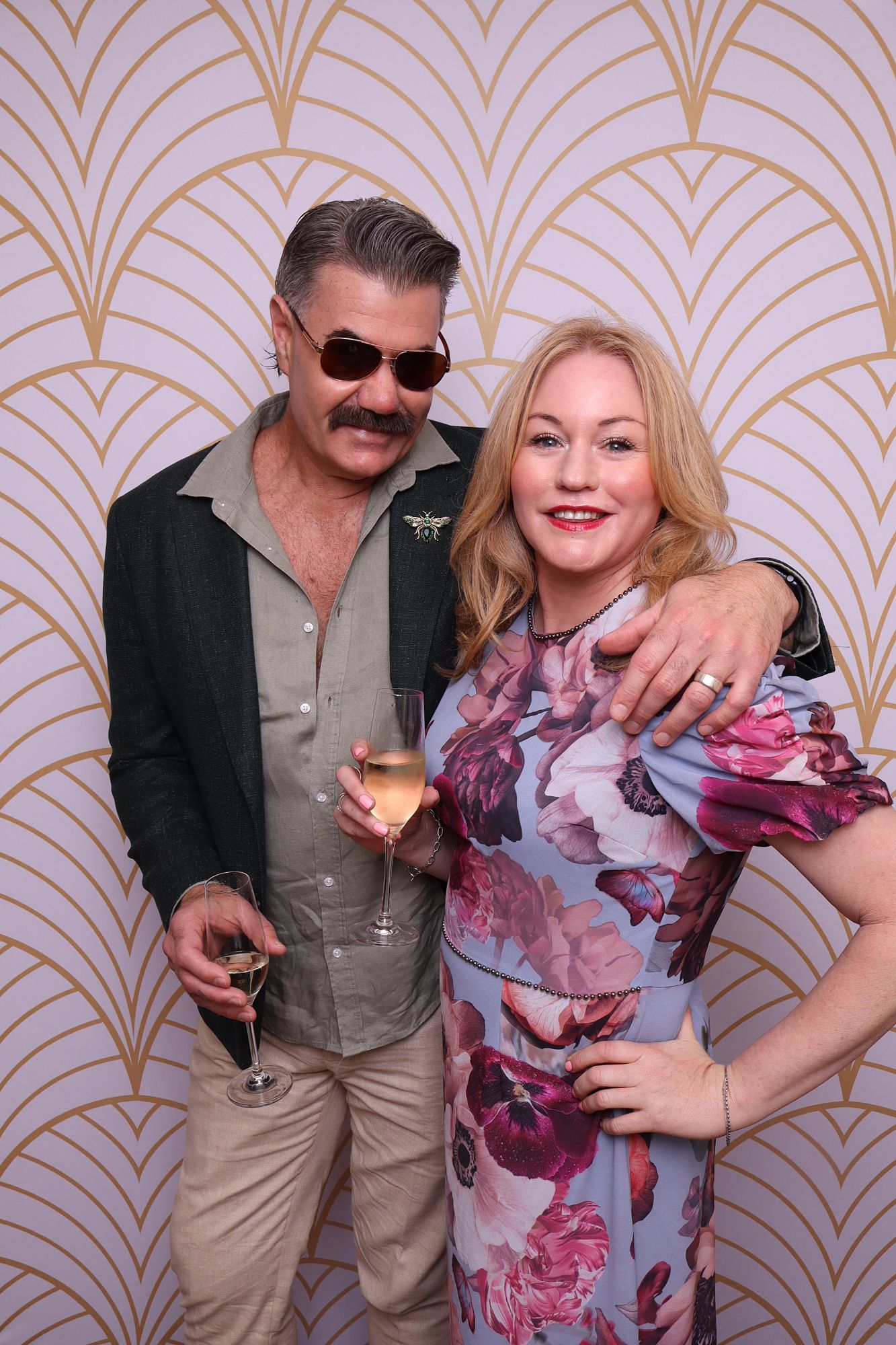 Two wedding guests with champagne in front of an art deco backdrop at the Ginninderry Homestead photo booth
